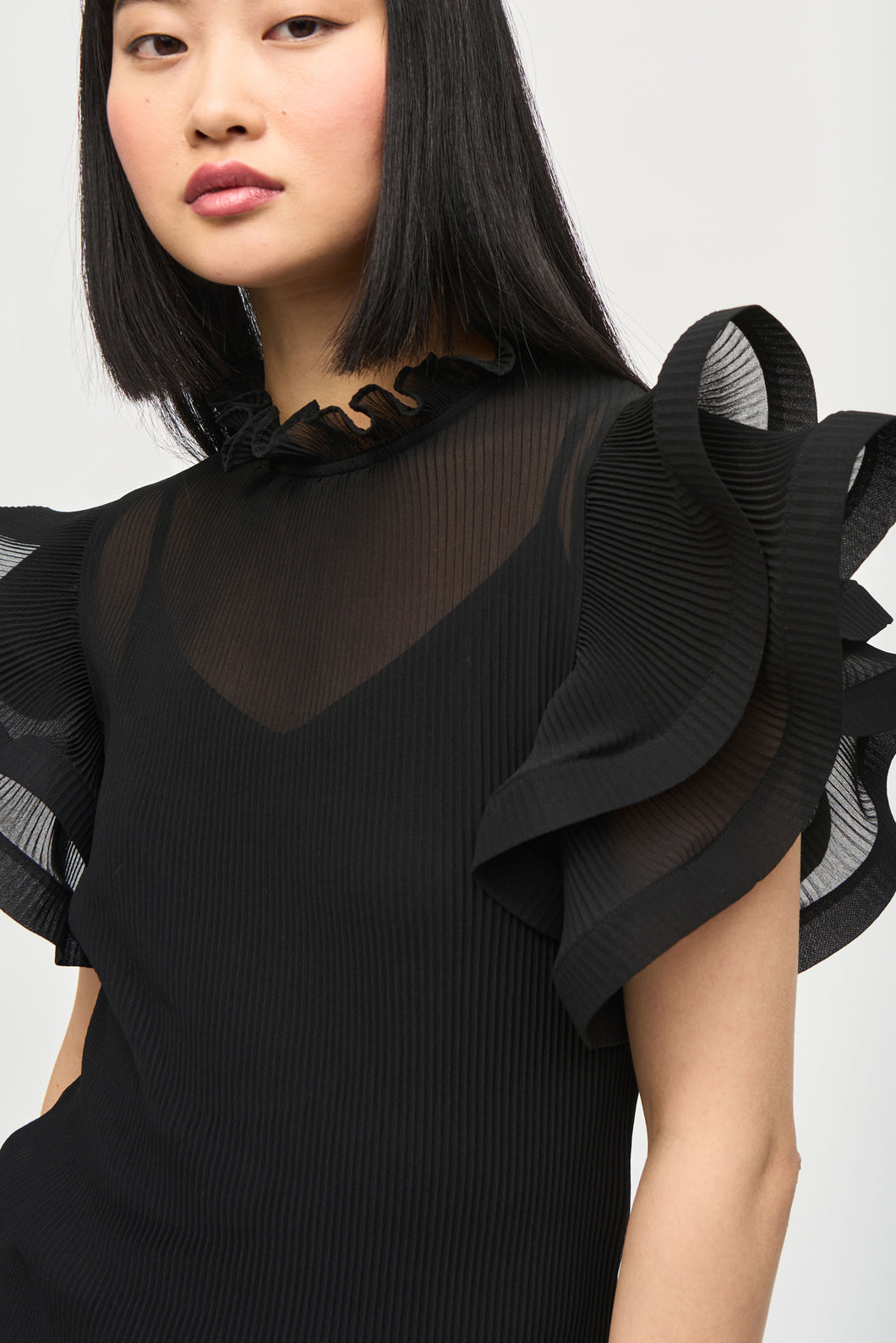 A feminine top with chiffon ruffles at the collar and sleeves, featuring a knit camisole for a soft, romantic look.