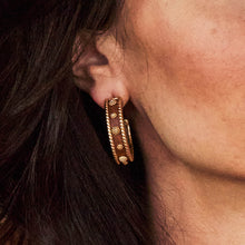 Load image into Gallery viewer, Chic gold hoop earrings with brown leather accents, known as Berry Medium Hoop Earrings - Teak, showcasing modern craftsmanship.
