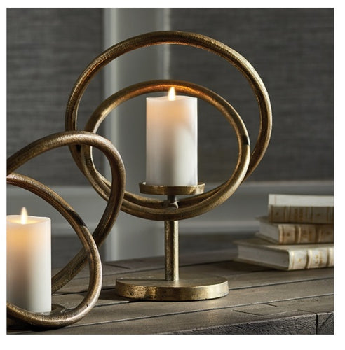 A refined display of two candles on a table, surrounded by a gold metal ring, exuding elegance and warmth.